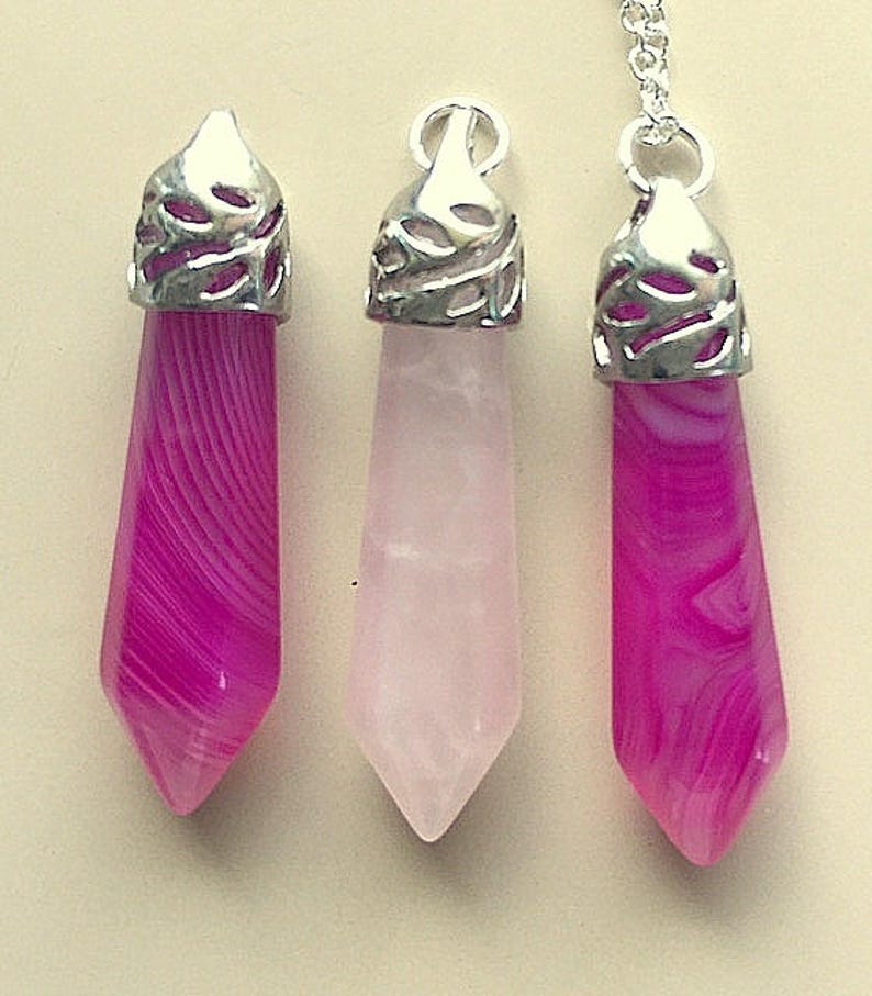 May include: Three silver pendant charms with pink and white agate stones. The charms are in the shape of a teardrop with a decorative silver top.