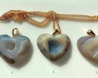 May include: Three heart-shaped agate pendants with gold chains. The pendants are all different colors and patterns, with one being a light blue and white, one being a light brown and white, and one being a dark brown and white.