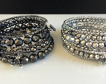 May include: Two bracelets made of black and silver beads. The bracelets are layered and have a star-shaped charm.