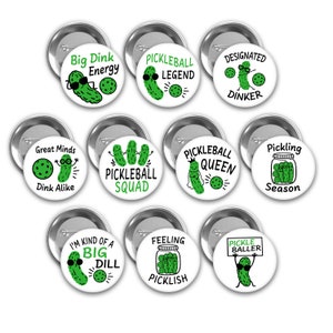 May include: Ten round white button pins with green pickle illustrations and pickleball-themed text. The text includes "Big Dink Energy", "Pickleball Legend", "Designated Dinker", "Great Minds Dink Alike", "Pickleball Squad", "Pickleball Queen", "Pickling Season", "I'm Kind of a Big Dill", "Feeling Picklish", and "Pickle Baller".