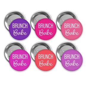 May include: Six round button pins with a silver backing. Each button has a different color background: purple, pink, red, magenta, coral, and lavender. The text on each button reads "BRUNCH Babe" in white cursive font.