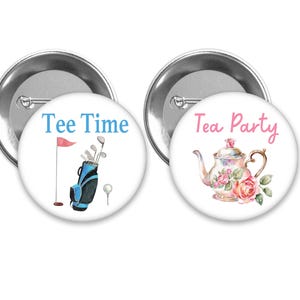 May include: Two round pinback buttons. One features a golf bag, golf clubs, a golf ball, and a flag with the text "Tee Time" in blue. The other button has a teapot with roses and the text "Tea Party" in pink.