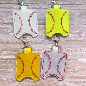 May include: Four different coloured hand sanitiser holders with a baseball stitch design. The holders are made of leather and have a silver metal keychain.