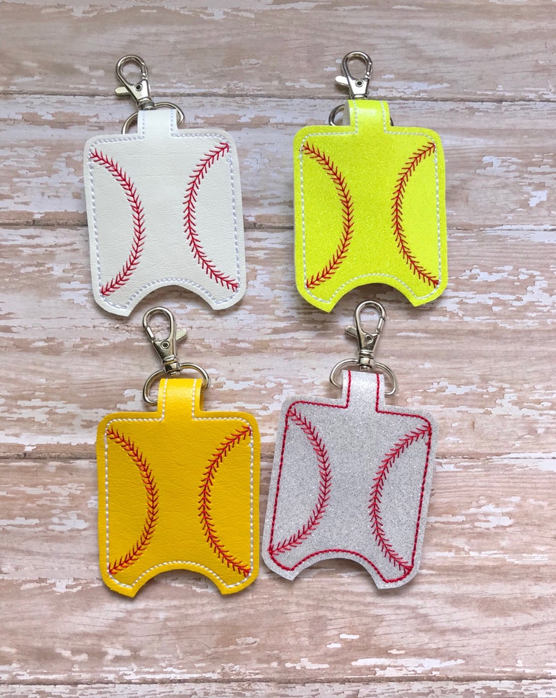 May include: Four different coloured hand sanitiser holders with a baseball stitch design. The holders are made of leather and have a silver metal keychain.