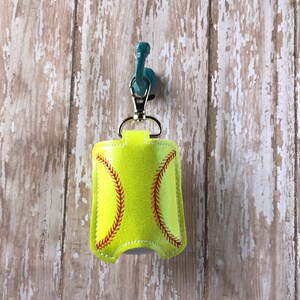 May include: A yellow and red softball-shaped hand sanitiser holder with a silver keychain.