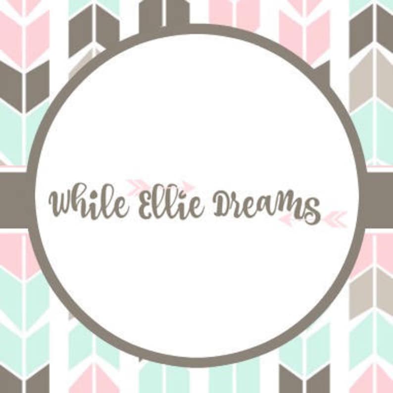 May include: A white circle with the text "while Ellie Dreams" in brown cursive lettering. The circle is surrounded by a brown and pink chevron pattern.