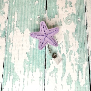 May include: Purple beaded starfish badge reel with a clear plastic badge holder.