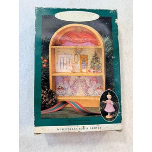 May include: A rectangular box for a Keepsake Ornament featuring The Nutcracker Ballet. The box displays a two-shelf display case illustration with a Christmas tree, candy canes, and a small figurine of a ballerina in a pink dress.