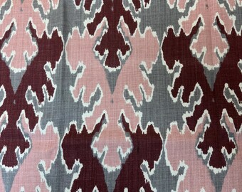 May include: Close-up of a fabric with a repeating pattern. The design features a gray background with a repeating pattern of pink and burgundy shapes outlined in white. The fabric has a textured appearance.