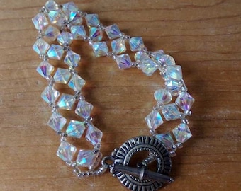 May include: A silver and iridescent crystal bracelet with a toggle clasp. The bracelet is made of multiple strands of faceted crystals.