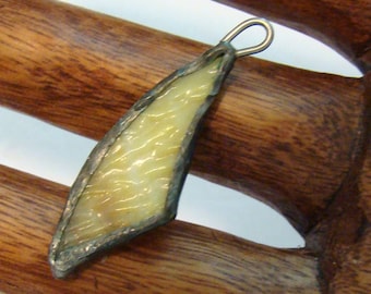 May include: A yellow glass pendant with a silver frame and a loop for hanging. The pendant is shaped like a leaf and has a textured surface.