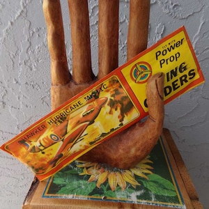 May include: Vintage toy airplane kit with a red, white, and blue box. The box has the text "Fly with Power Prop Gliders" and "Hawker Hurricane Mk.IIC".