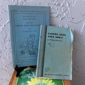 May include: Two blue play scripts for the play "Gabriel, Blow Your Horn!" by William Ellis Jones. The script on the left is from the class of 1943 at Perley High School. The script on the right is from Sergel's Royalty Plays, The Dramatic Publishing Company.
