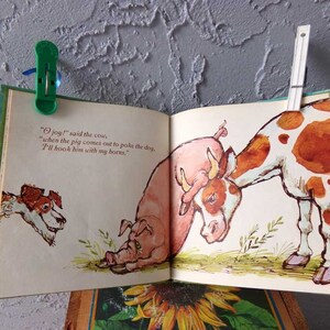 May include: An illustration from a children's book showing a cow with brown and white spots, a pig, and a dog. The cow is saying, "joy!" said the cow, "when the pig comes out to poke the dog, I'll hook him with my horns."