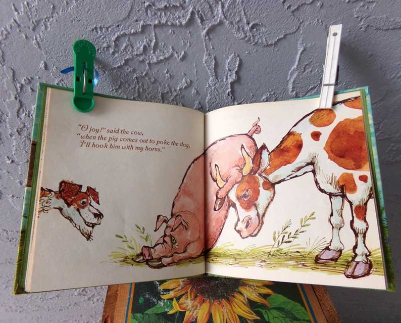 May include: An illustration from a children's book showing a cow with brown and white spots, a pig, and a dog. The cow is saying, "joy!" said the cow, "when the pig comes out to poke the dog, I'll hook him with my horns."