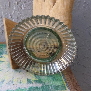May include: A clear glass ashtray with a raised rim and a printed image of the US Capitol building in Washington, D.C.