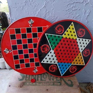 May include: Two vintage game boards, one with a checkerboard pattern and the other with a star-shaped game board with red, yellow, green, and blue sections. Both boards are red with black details and have a dragon design.