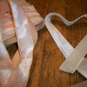 May include: Two rolls of pink velvet ribbon with a satin sheen. One roll is folded into a heart shape.