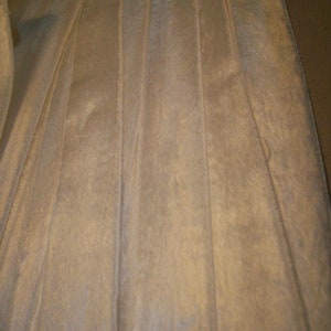 May include: White satin ribbon with vertical pleats. The ribbon has a subtle sheen and a smooth texture.