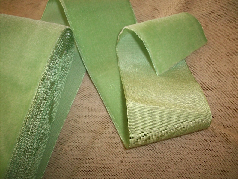 May include: A roll of green velvet ribbon with a satin finish. The ribbon is folded in half and the ends are curled.