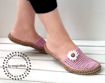 May include: Pink crocheted slippers with a white crocheted flower and a brown button in the center. The slippers have a jute sole.