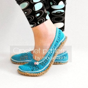Puede incluir: Un par de zapatillas azules de ganchillo con suela de yute. Las zapatillas tienen un delicado diseño floral y las lleva una persona con leggings de estampado blanco y negro.
