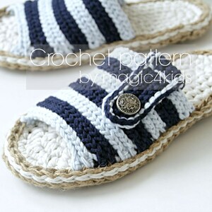May include: Crochet pattern by magic4kids. A pair of blue and white striped crochet slippers with a jute trim. The slippers have a button closure.