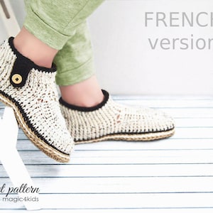 Puede incluir: Un par de zapatillas de crochet con ribete marrón y un detalle de botón. Las zapatillas están hechas con hilo beige y tienen una suela de yute. El texto "FRENCH version" es visible en el fondo.