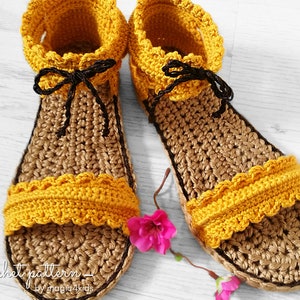 May include: A pair of crocheted sandals in brown and yellow with black ties. The sandals have a scalloped edge and are made with a textured stitch.