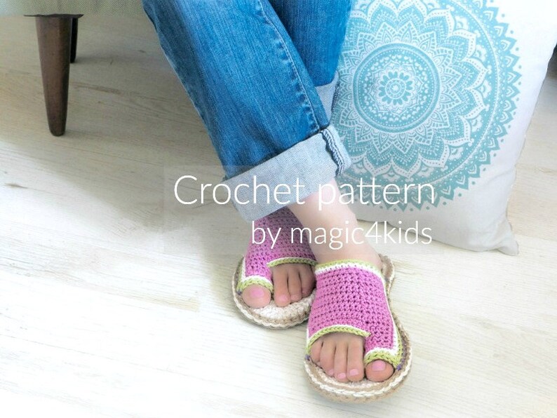 May include: Crochet pattern for pink and green sandals with a toe loop. The sandals are worn by a person sitting on a white cushion with a blue mandala pattern. The text "Crochet pattern by magic4kids" is visible below the sandals.