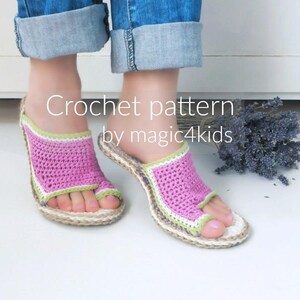 May include: A pair of pink and green crocheted sandals with a woven sole. The sandals are being worn by a person with their feet crossed.
