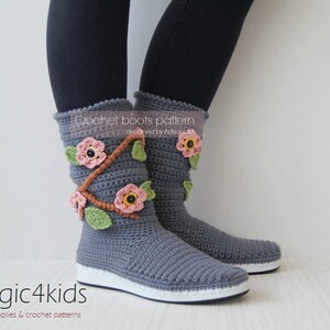 May include: Gray crochet boots with pink and brown flower embellishments. The boots are designed by Adora and are part of the magic4kids crochet pattern collection.