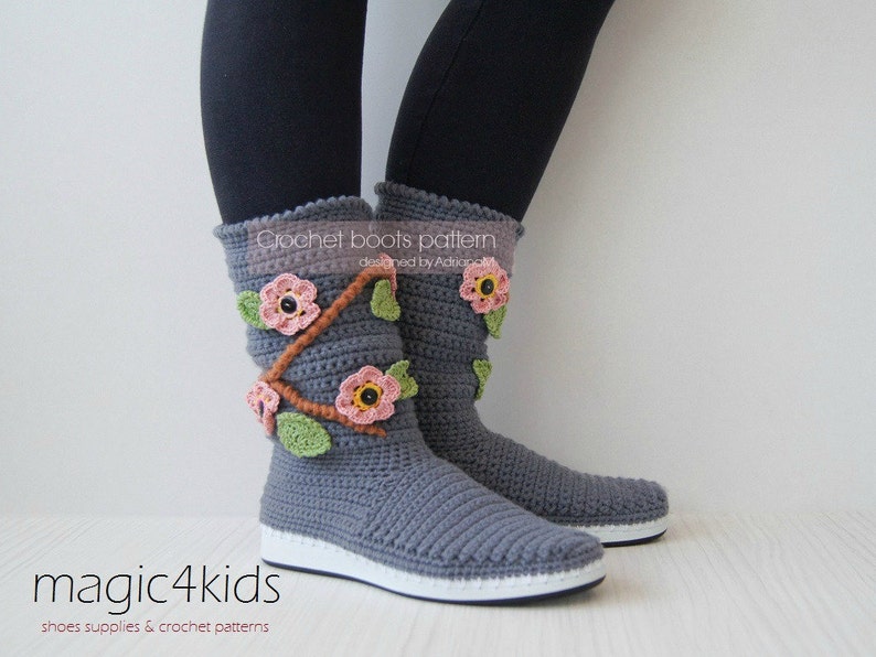 May include: Gray crochet boots with pink and brown flower embellishments. The boots are designed by Adora and are part of the magic4kids crochet pattern collection.