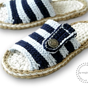 May include: A pair of blue and white striped crocheted slippers with a brown jute sole. The slippers have a button closure and are made with a simple stitch pattern.