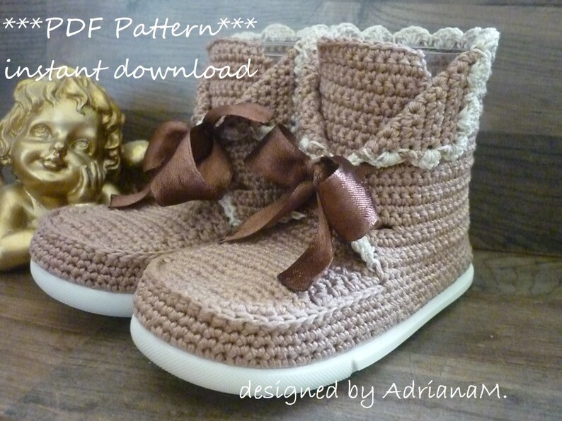 May include: A pair of brown crocheted booties with white crocheted trim and a brown satin ribbon. The booties have a white sole and are designed by AdrianaM.