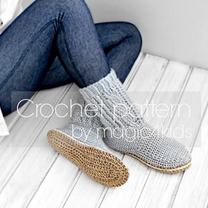 Puede incluir: Calcetines de lana grises de crochet con suela tejida marr&oacute;n. Los calcetines los lleva puestos una persona sentada en un suelo de madera blanco. El texto "Crochet pattern by magic4kids" es visible en la imagen.