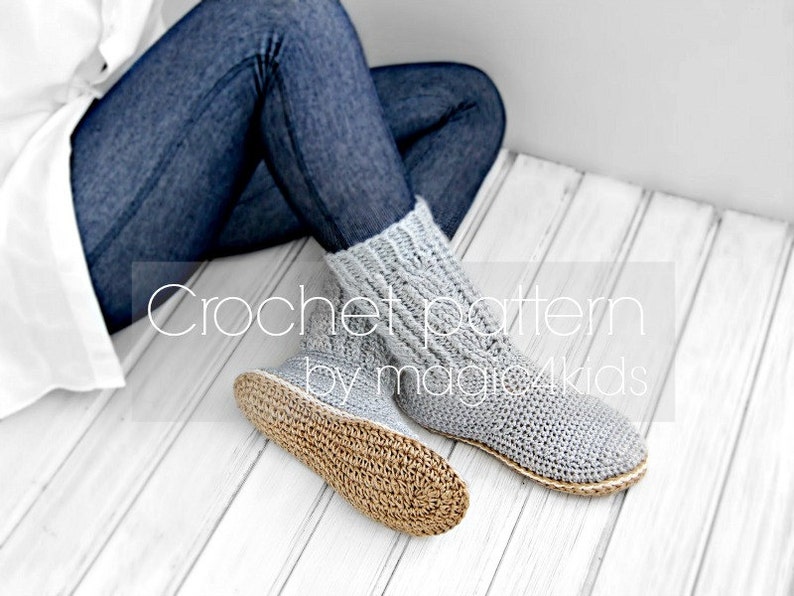 Puede incluir: Calcetines de lana grises de crochet con suela tejida marr&oacute;n. Los calcetines los lleva puestos una persona sentada en un suelo de madera blanco. El texto "Crochet pattern by magic4kids" es visible en la imagen.