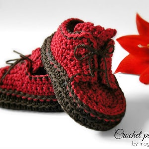 Puede incluir: Botas de bebé de ganchillo de color rojo y marrón con un detalle de encaje. Patrón de ganchillo de magia4kids.