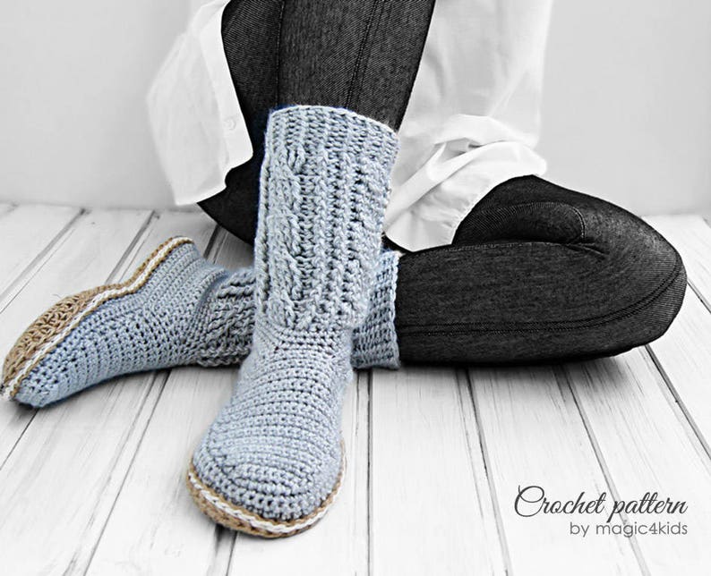 Puede incluir: Un par de pantuflas de crochet azul claro con un ribete de crochet marr&oacute;n claro. Las pantuflas las lleva puestas una persona sentada en un suelo de madera. El texto "Crochet pattern by magic4kids" es visible en la parte inferior de la imagen.