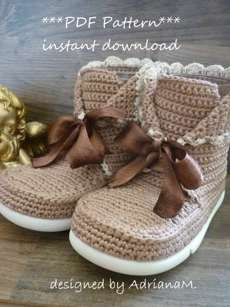 May include: A pair of brown crocheted booties with white soles and brown ribbon laces. The booties have a crocheted trim around the top. The text "***PDF Pattern*** instant download designed by Adrianam." is visible at the bottom of the image.