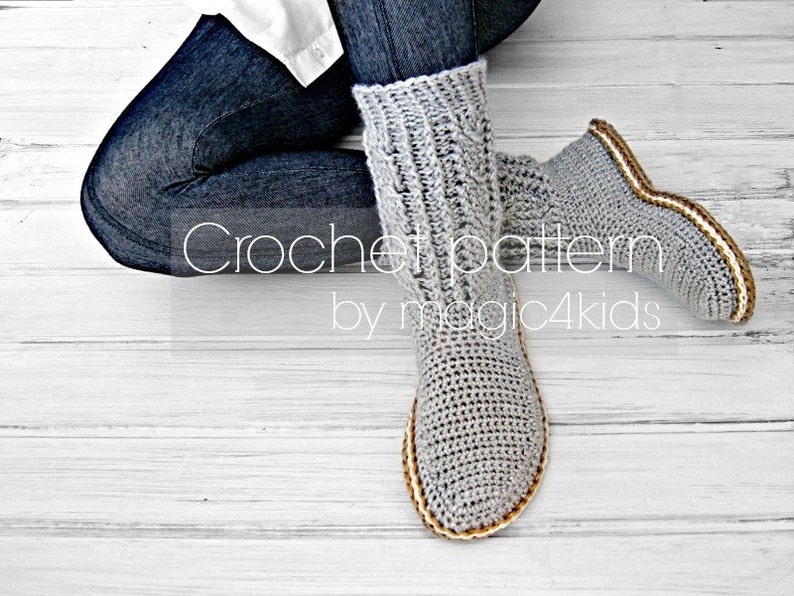 Puede incluir: Pantuflas de crochet grises con ribete marr&oacute;n y blanco. Las pantuflas las lleva puestas una persona sentada en un suelo de madera blanco. El texto "Crochet pattern by magic4kids" es visible en la imagen.