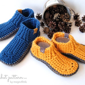 Puede incluir: Dos pares de zapatillas de crochet, un par es azul con ribete gris y el otro par es amarillo con ribete gris. Las zapatillas están sobre una superficie blanca.