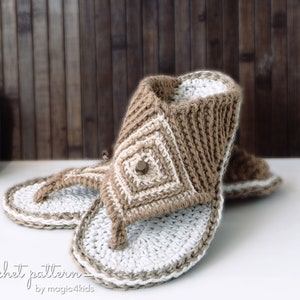Peut inclure: Sandales en crochet de couleur marron et blanche avec un bouton en bois. Les sandales sont posées sur une surface blanche.