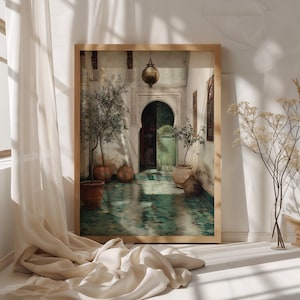 Op de afbeelding: Een ingelijste prent van een gewelfde deuropening met een groene deur, potplanten en een turquoise betegelde vloer. De prent heeft een houten lijst en staat tegen een witte muur. Boven de deuropening hangt een lantaarn.