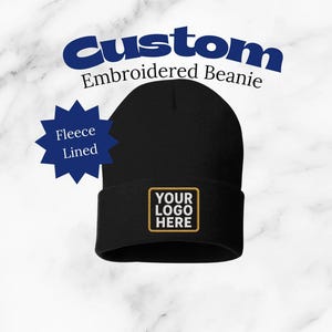 May include: Black custom embroidered beanie with a fleece lining. The beanie features a rectangular patch with the text "YOUR LOGO HERE" in a gold border. The words "CUSTOM Embroidered Beanie" are arched above the beanie.
