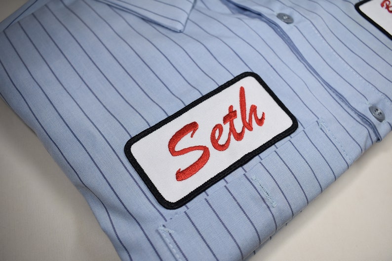 May include: A blue and white striped shirt with a white name tag that says "Seth" in red cursive lettering.