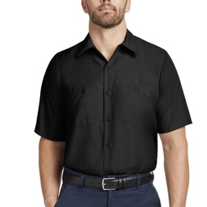 Puede incluir: Una camisa negra de manga corta con botones, cuello cl&aacute;sico y dos bolsillos en el pecho, combinada con pantalones azul oscuro y un cintur&oacute;n de cuero negro con una hebilla rectangular plateada, formando un conjunto de uniforme est&aacute;ndar.