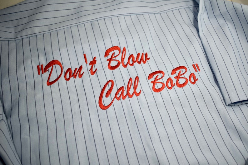 Puede incluir: Una camisa a rayas azules y blancas con texto bordado en rojo que dice "Don't Blow Call BoBo".