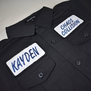 May include: Black button-up shirt with two white patches. The left patch says "KAYDEN" in blue lettering. The right patch says "CHAOS COLLISION" in blue lettering.