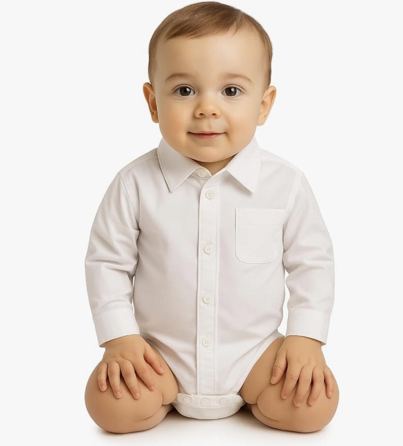 May include: A crisp white long-sleeved button-down bodysuit featuring a classic pointed collar, a single chest pocket, and a front button placket. The garment is designed with a structured shirt-style top that transitions into a snap-closure bottom.